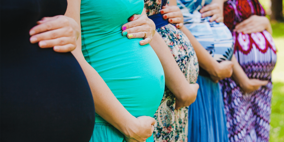 A group of pregnant women posing holding their bellies