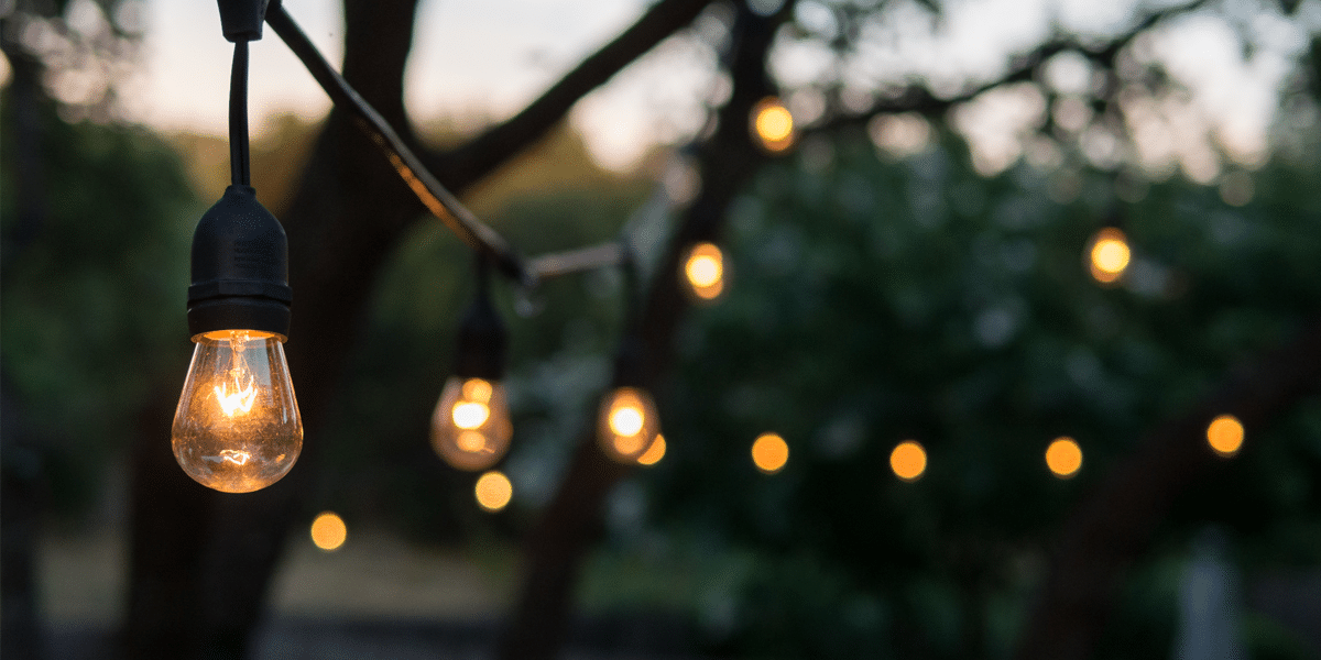 A string of Edison bulb lights outdoors at dusk